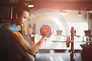 Man hand holding dumbbell exercise in gym. Fitness muscular body with set of black weights in the gym background