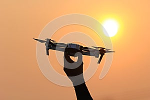 Man hand holding flying drone on sunset background