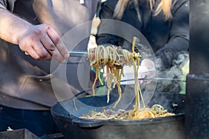 A man hand holding a fork with homemade noodles. Lagman. Taditional dish of Middle East cuisine with noodles, beef and vegetables