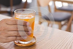 Man hand holding a glass of orange juice.