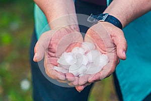 Man hand holding a hail after hailstorm