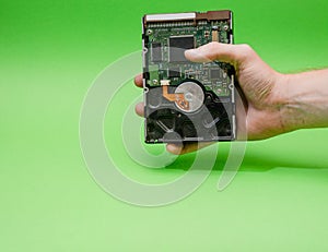 Man hand holding 3.5 HDD on green background. Mining on hard disk drive concept