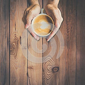 Man hand holding hot cup of coffee, and heart shape