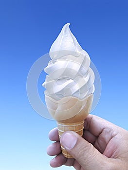 Man hand holding an ice cream cone on background. the blue sky