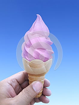 Man hand holding an ice cream cone on background. the blue sky