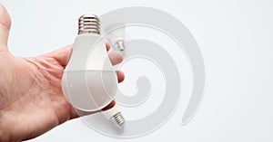 Man hand holding led light bulb on white background. Closeup. Energy saving. Point of view shoot. Energy efficient lighting choice