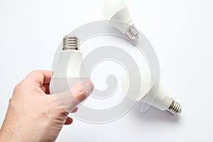 Man hand holding led light bulb on white background. Closeup. Energy saving. Point of view shoot. Energy efficient lighting choice