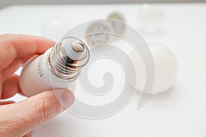 Man hand holding led light bulb on white background. Closeup. Energy saving. Point of view shoot. Energy efficient lighting choice