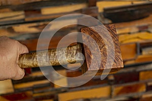 Man hand holding a mallet hammer made of burl wood tools for used by carpenter in workshop on blurred background