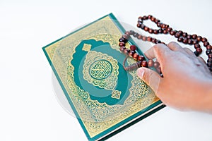 Man hand holding a muslim rosery beads, tasbih with quran asid