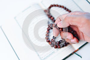 Man hand holding a muslim rosery beads, tasbih with quran asid