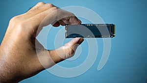Man hand holding NVME PCIE SSD hard drive disk having high read and write speed memory.Grey Background.