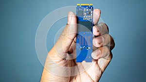 Man hand holding NVME PCIE SSD hard drive disk having high read and write speed memory.Grey Background.