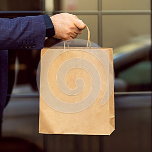 Man hand holding a paper bag outside. Using a paper bag to save environment concept