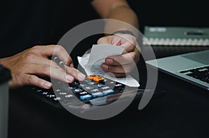 Man hand holding pen and calculator expense or tax receipt. business finance concept