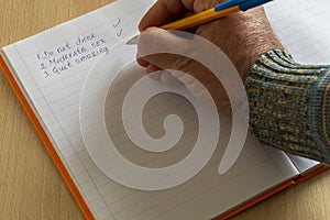 Man Hand Holding Pencil Over Open Notebook With Written Goals For Long Life