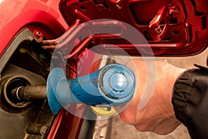 A man hand holding pump filling gasoline. Pumping petrol into the tank. A car refuel on gas station