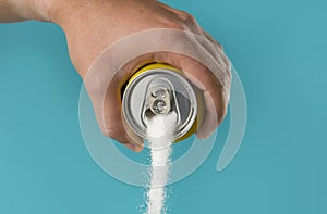 Man hand holding refresh drink can pouring sugar stream in sweet and calories content of soda and energy drinks