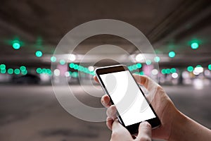 A man hand holding smart phone device with car park bokeh background.