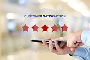 Man hand holding smart phone and red five star over blur background, customer excellent rating satisfacation, customer feedback