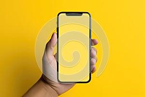 Man hand holding smartphone with blank yellow screen on yellow background. Mockup cell phone screen