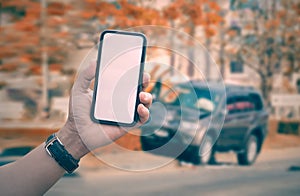 Man hand holding smartphone with car crash accident background