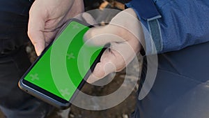 Man hand holding a smartphone touching phone with vertical green screen