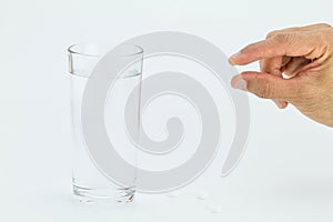 Man hand holding white pill with glass of water on white background