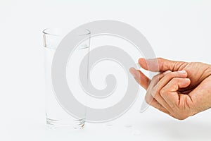 Man hand holding white pill with glass of water on white background