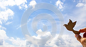 Man hand holding wooden bird on cloud sky background. The development of the imagination, copy space