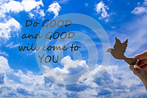 Man hand holding wooden bird on cloud sky background. Words `Do good and good will come to you` The development of the imaginati