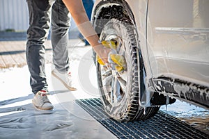 man hand holding yellow sponge cleaning car