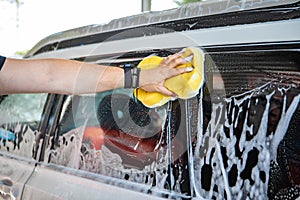 man hand holding yellow sponge cleaning car