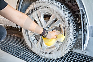 man hand holding yellow sponge cleaning car