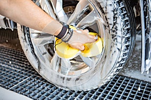 man hand holding yellow sponge cleaning car