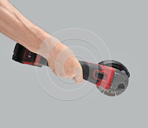 Man hand holds brushless cordless angle grinder on gray background