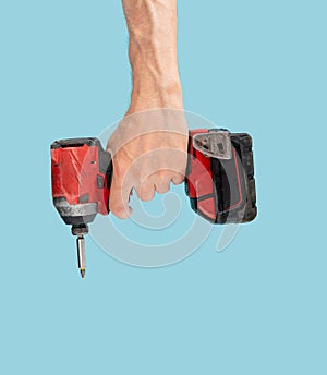 Man hand holds brushless cordless impact driver that comes from abobove on pastel blue background