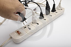 Man hand inserting a plugs into multi electrical power strip on white background , unsafety concept