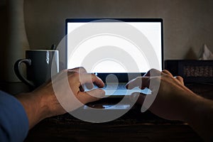 Man hand on laptop keyboard with blank screen monitor on night. View from his position.