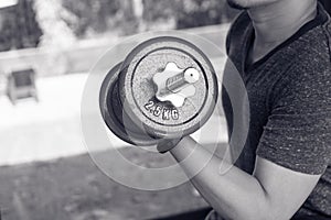 Man hand lifting the steel dumbbell in a gym muscle-building black and white image, life and fitness concept with copy space