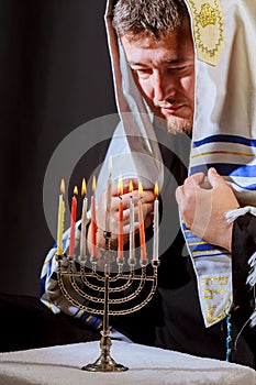 man hand lighting candles in menorah on table served for hanukka photo