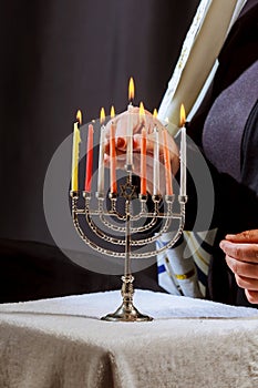 man hand lighting candles in menorah on table served for hanukka photo