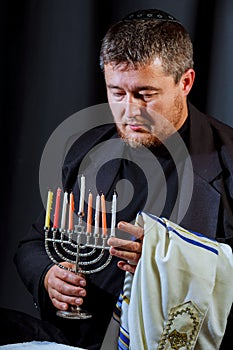 man hand lighting candles in menorah on table served for hanukka photo