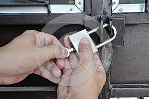 Man hand locking steel door with padlock