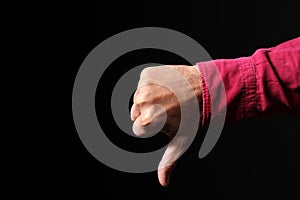 Man hand makes thumb down gesture isolated on black background with copy space for your text