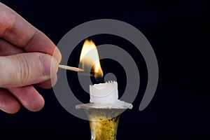 Man hand with Matchstick light flame on candle in candlestick