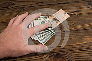 A man hand and a mousetrap with bait money dollars banknotes