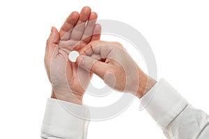 Man hand with one big white pill isolated on white background. White shirt, business style. Medicament and food supplement for