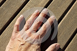 Man hand over sunny teak wood lines