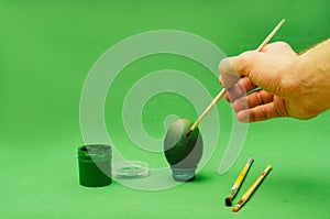 Man hand paints Easter egg with brush
